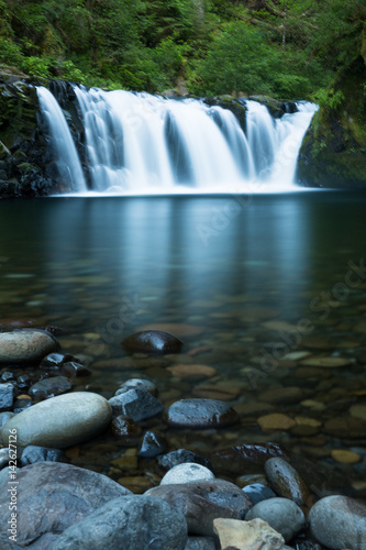 Wide waterfall over calm pool smoothed with long exposure