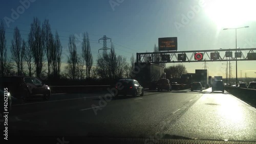 Driving on the busy M6 motorway with sun shining down on the busy road photo