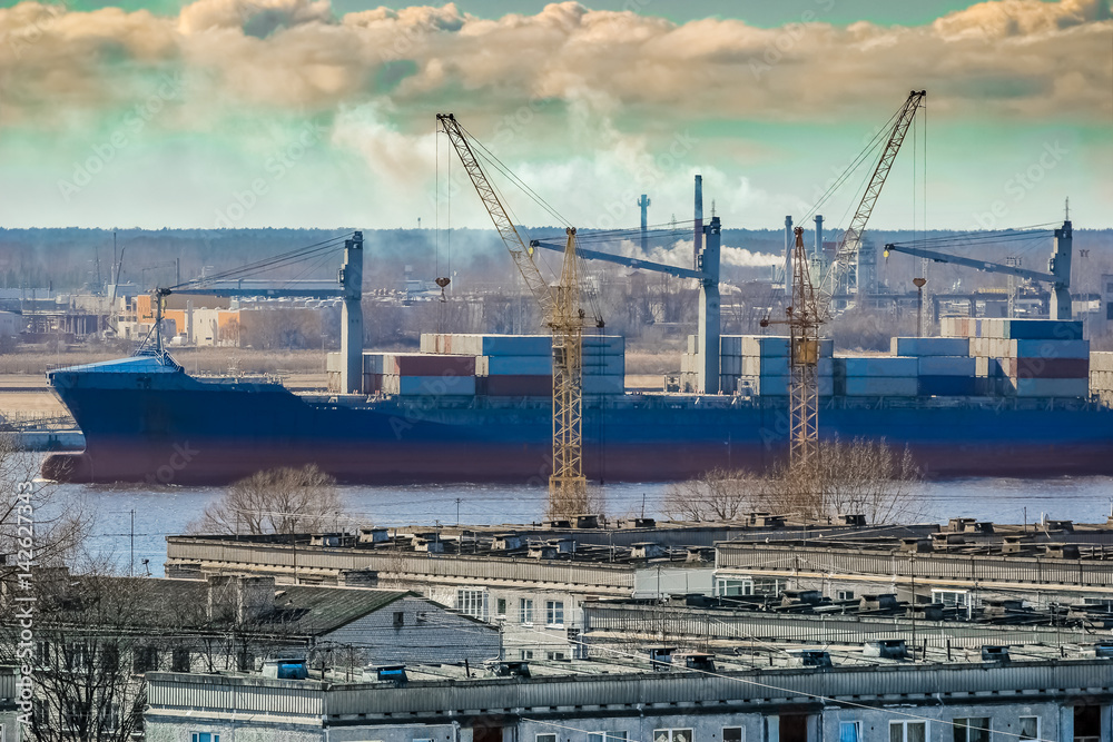 Blue cargo container ship moving past the Riga city