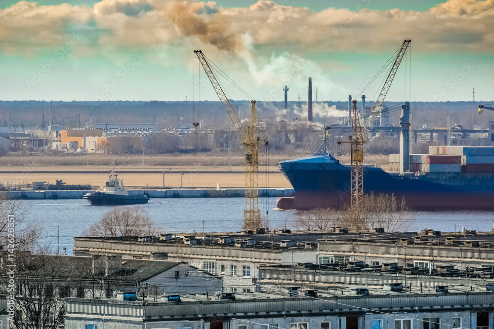 Blue cargo container ship moving past the Riga city
