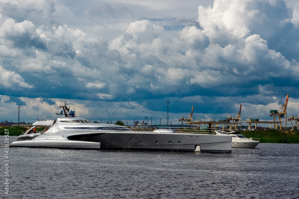 Large silver trimaran. Luxury yacht sailing by the river in Riga