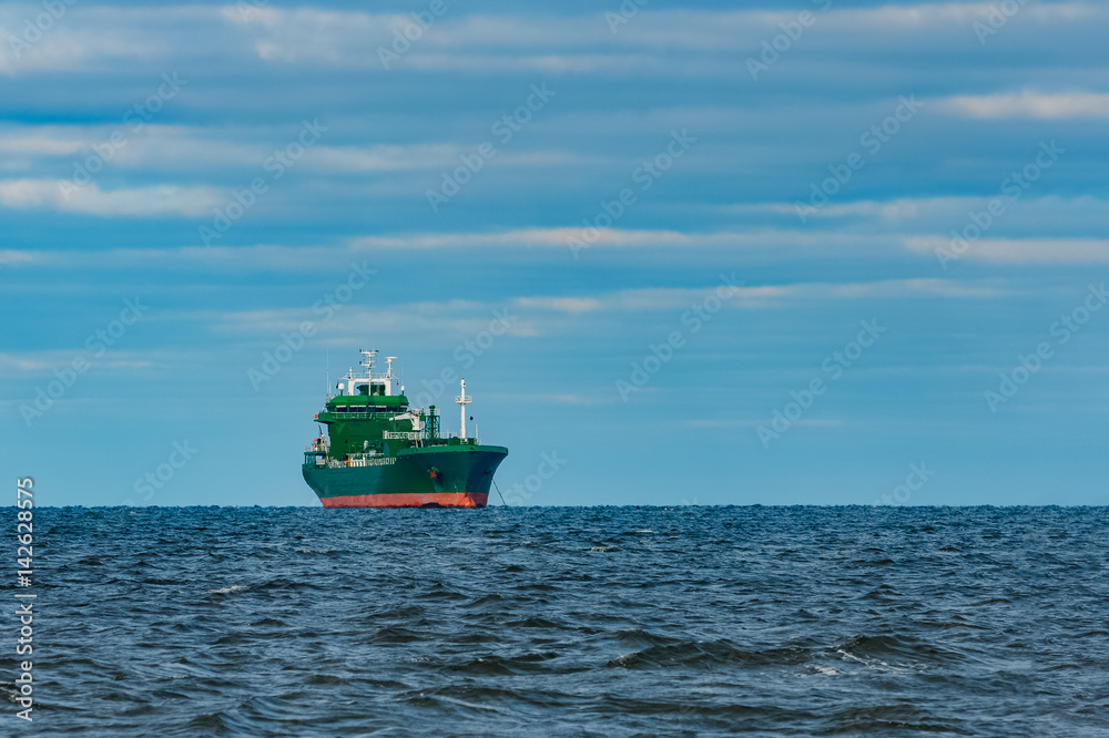 Green cargo ship moored in still Baltic sea water