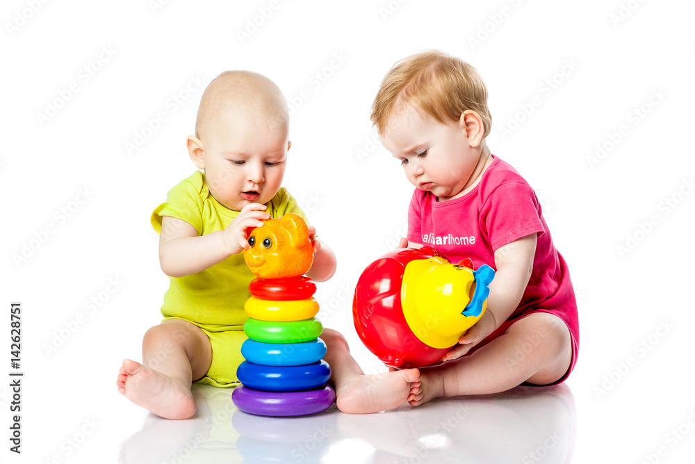 Two kids play dice, pyramid, tumbler in bright clothes Two kids play dice, pyramid, tumbler in bright clothes