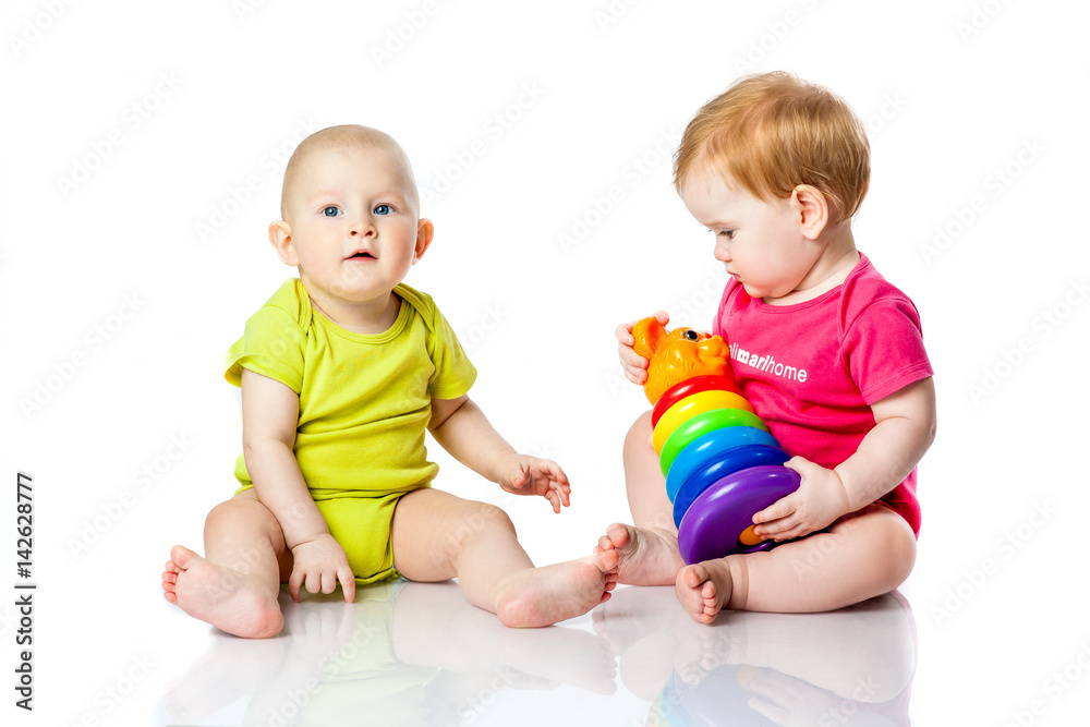 Two kids play dice, pyramid, tumbler in bright clothes Two kids play dice, pyramid, tumbler in bright clothes