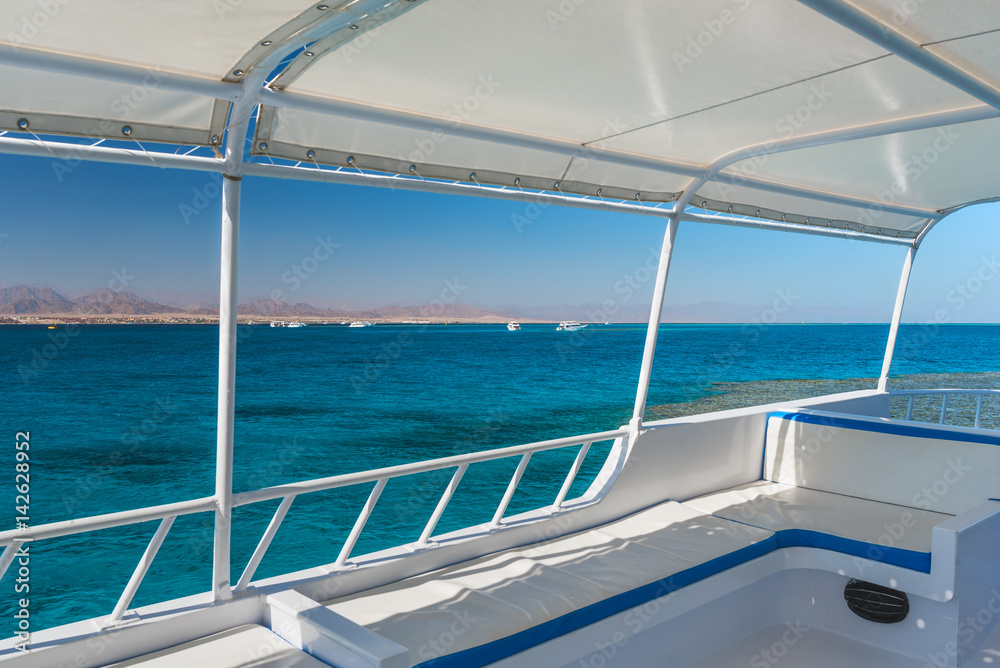 View at the coral sea from a white yacht. Perfect place for snorkeling. Summer vacation at sea with turquoise clear water.