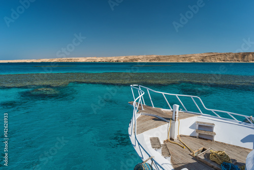 View at the coral sea and white yacht. Perfect place for snorkeling. Summer vacation at sea with turquoise clear water. © ianachyrva