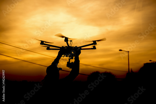 Silhouette man holding drone ready for take of background sunset.