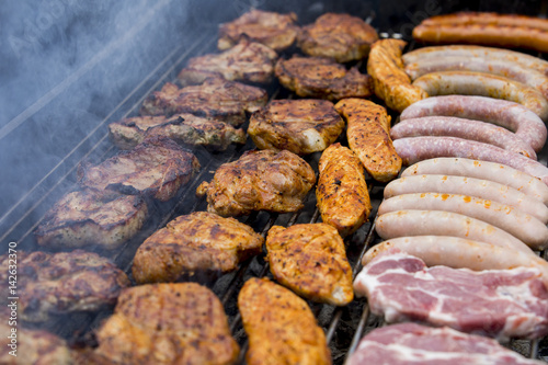 Fleisch und Wurst werden auf einem Grill zubereitet