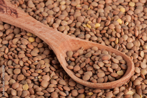 Lentils in a wooden spoon as background