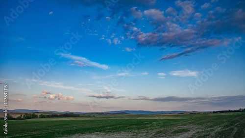 Clouds moving over field, blue sky time lapse video