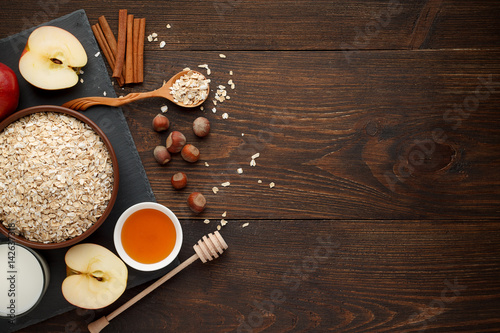 Ingredients for oatmeal on dark wooden table. Concept of healthy food.