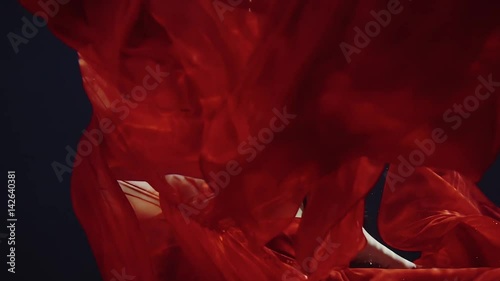 a young woman in a red dress swimming under water like in a fairy tale