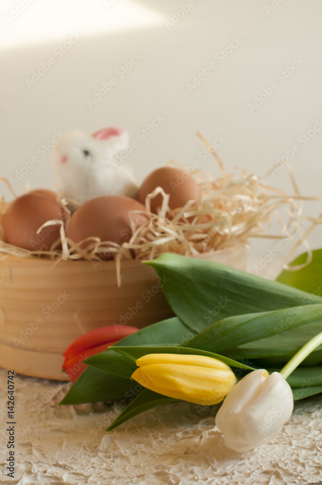 Easter holiday basket with eggs, flowers and easter bunny on rustic wooden