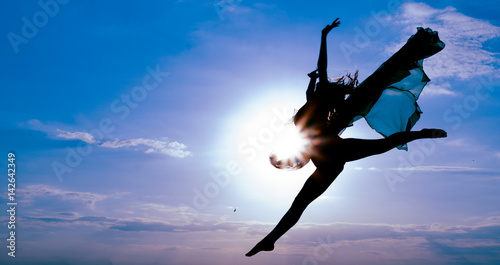 beautiful girl teen in gymnastic jump against blue sky