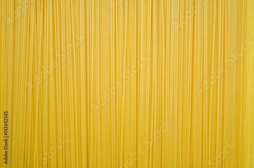 Uncooked pasta spaghetti macaroni yellow background