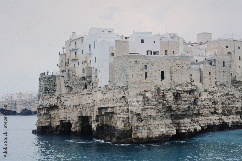The unique view of Polignano a mare, Italy, a medieval small town on a cliff by the sea, in a cloudy day with a thin mist.
