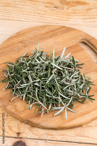 Sliced and chopped rosemary plant on the wooden board