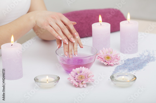 Woman hands receiving a hand scrub peeling by a beautician in beauty salon. SPA manicure, hand massage and body care. Close up, shallow dof.