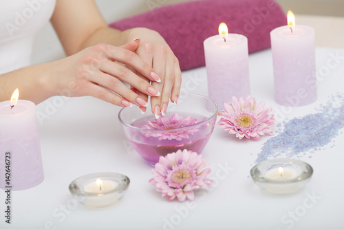 Spa Beauty Salon. Closeup Of Female Hands With Perfect Natural Fingernails Soaking In Hand Bath Before Manicure. Woman Washing Perfect Nails In Transparent Bowl Of Water. Nail Care. High Resolution