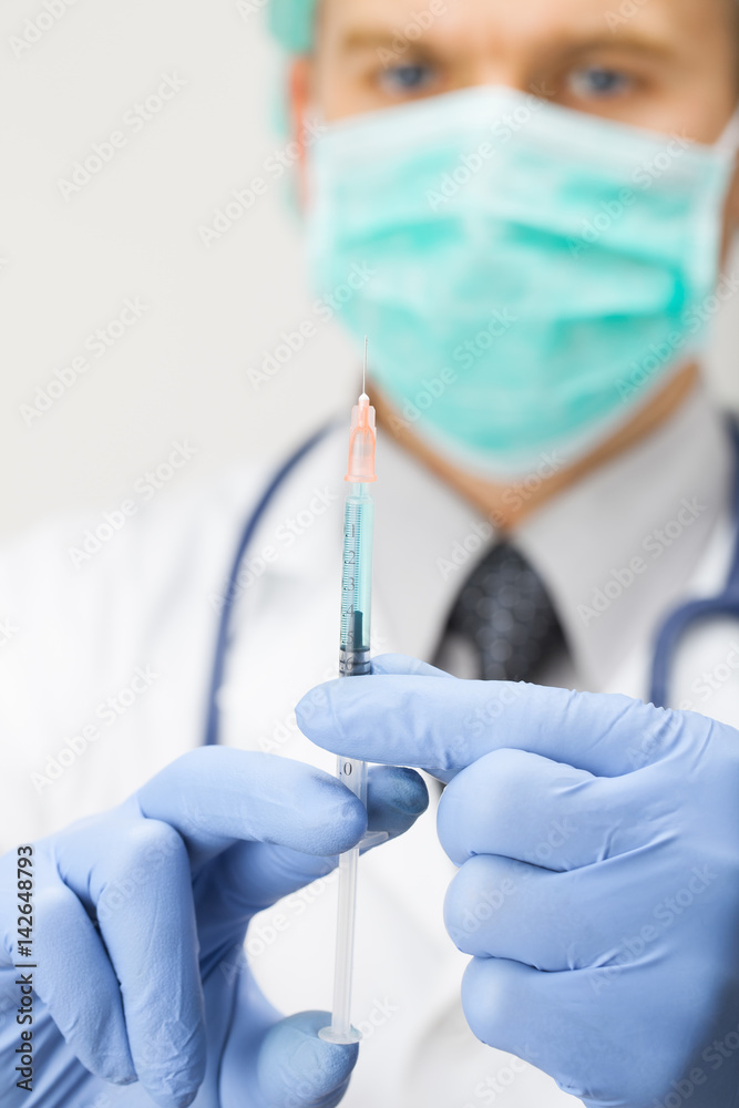 Doctor holding syringe with two hands and getting ready to make injection Doctor holding syringe with two hands and getting ready to make injection