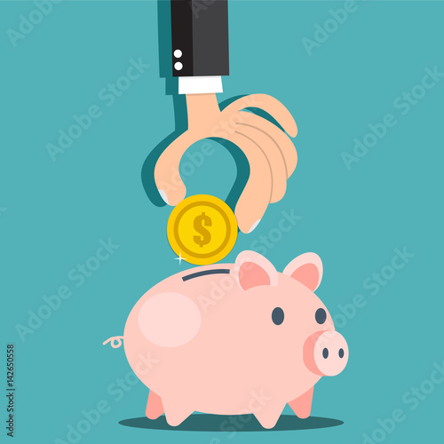Businessman hand putting a coin into a piggy bank. Saving and investing money concept. 