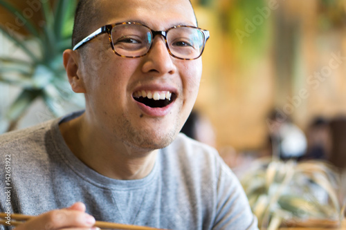 Foto カフェで笑顔を見せる日本人男性のポートレート｜メガネ・坊主頭・ライフスタイル写真