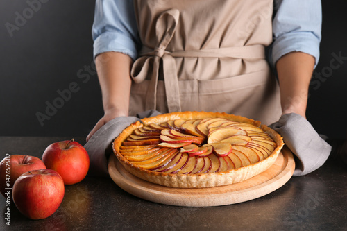 Woman putting homemade apple pie on table