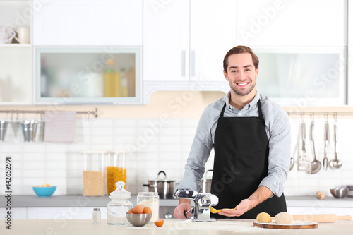 Man rolling dough for pasta on table