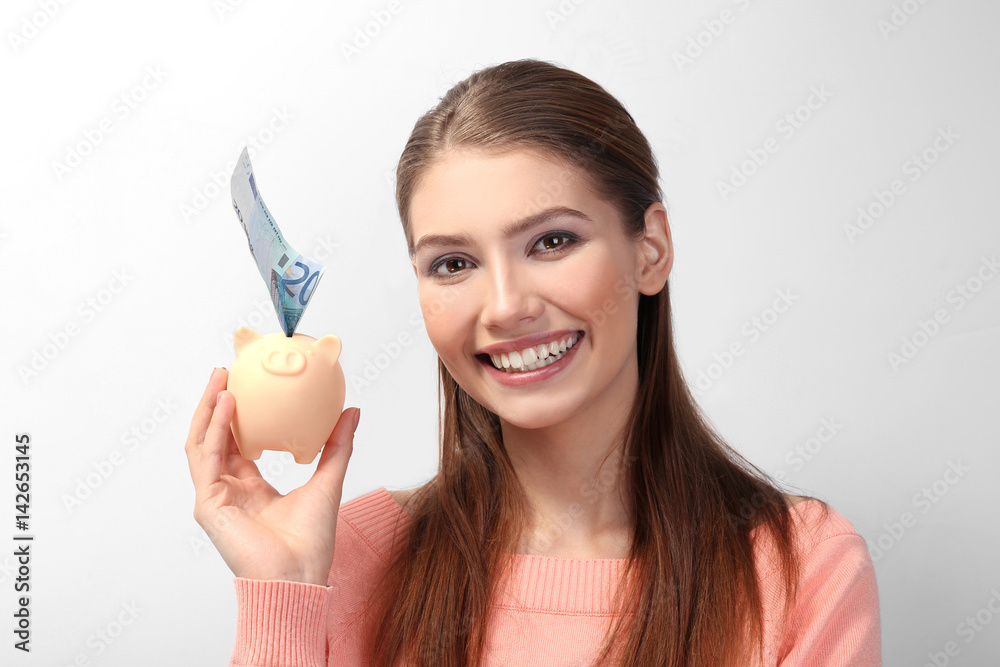 Beautiful young woman with piggy bank on light background Beautiful young woman with piggy bank on light background