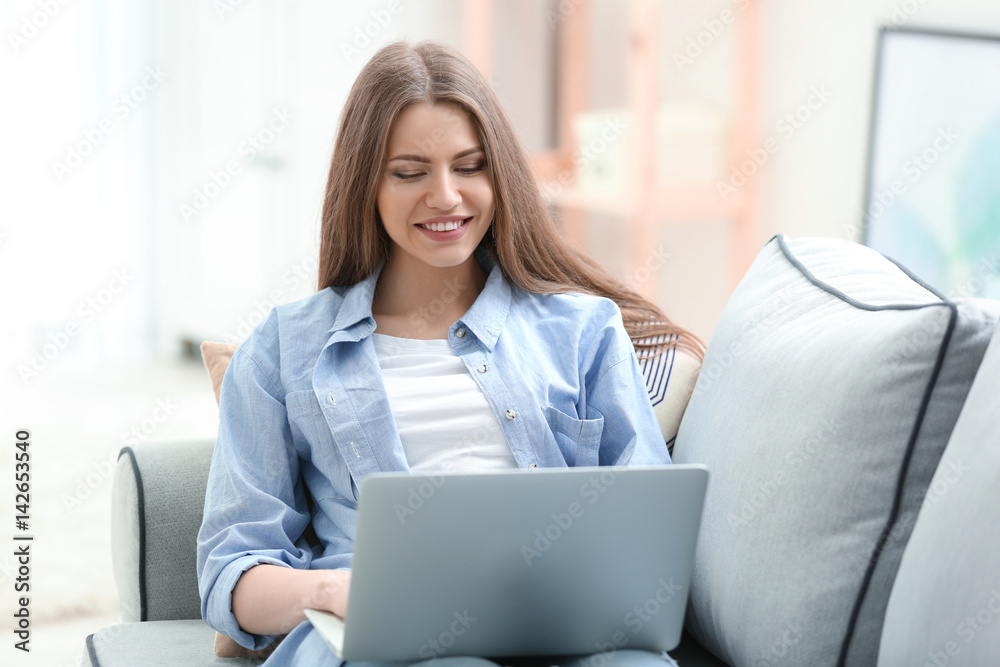 Beautiful young woman with laptop resting at home