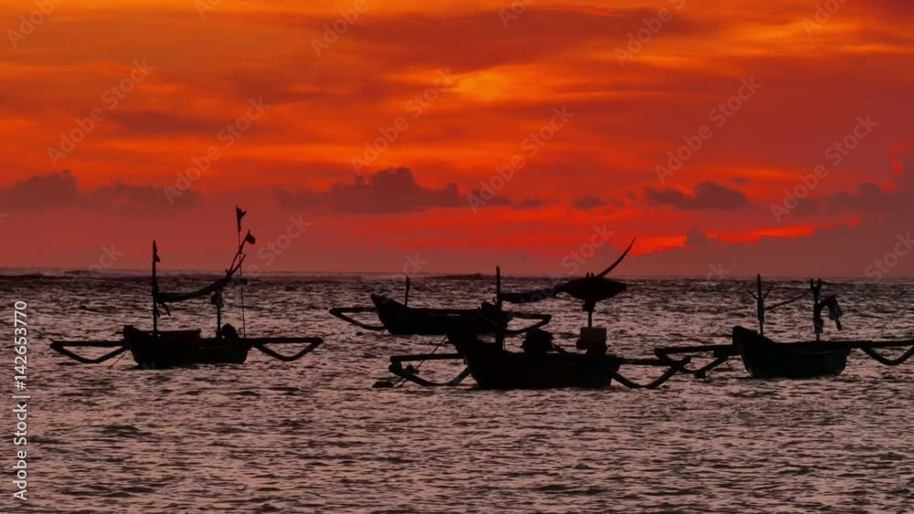 Black silhouettes of fishing boats at beautiful orange sunset in bali island Black silhouettes of fishing boats at beautiful orange sunset in bali island