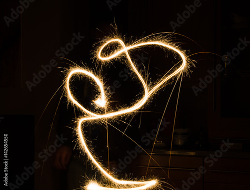 A glowing red hot sparkler light trail isolated in dark environment using slow shutter speed.