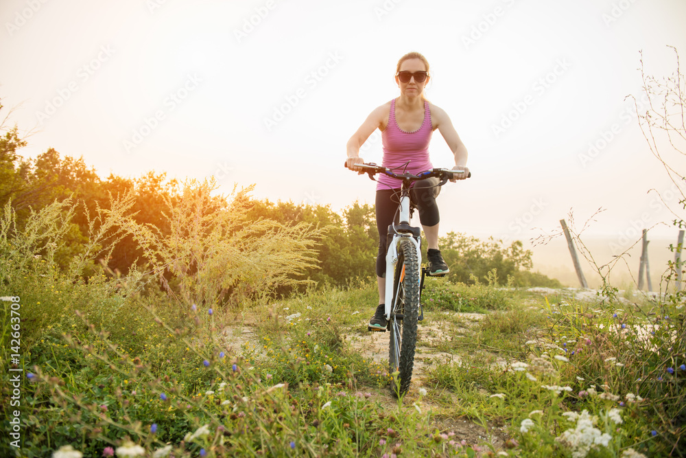 Girl on mountain bike rides on the trail on a beautiful sunrise
