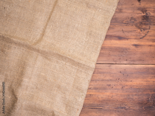 Old rural wooden table boards and burlap vintage background, photo top view. Hessian, sacking texture on wooden background for your design. Copy space for your message.