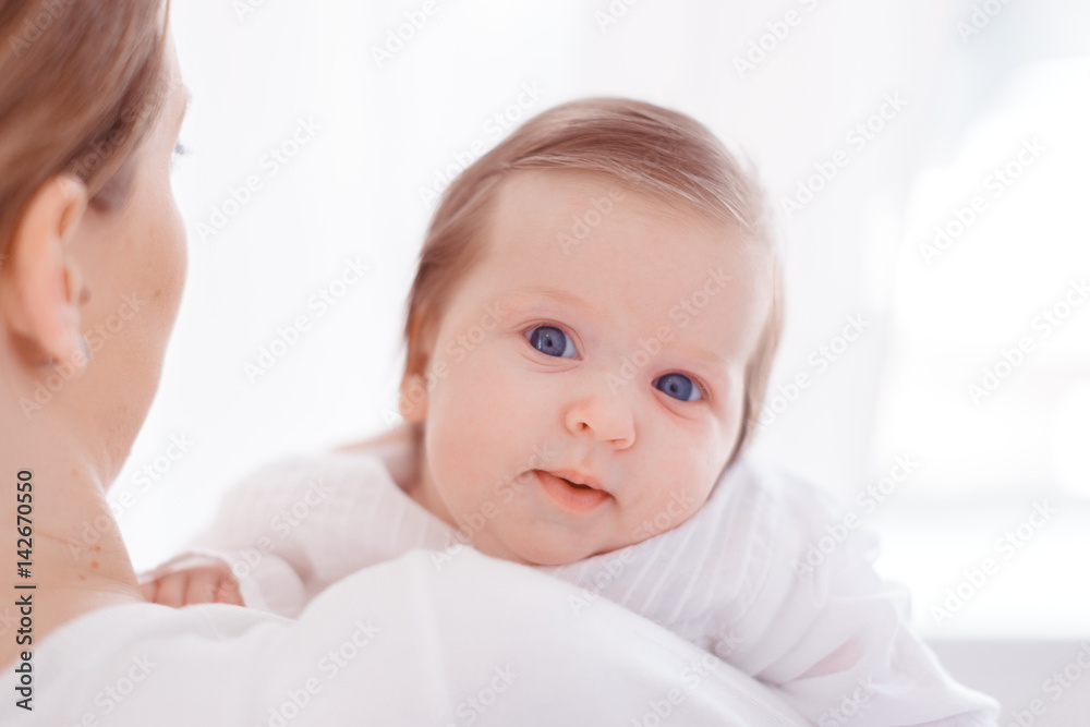 Young mother and newborn baby in white bedroom Young mother and newborn baby in white bedroom