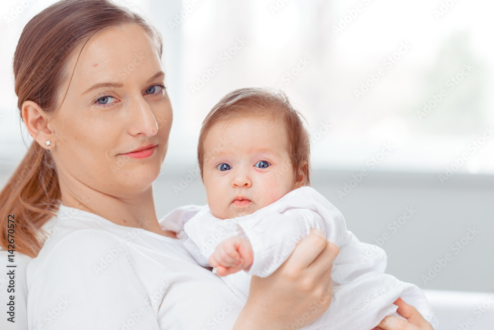 Young mother and newborn baby in white bedroom