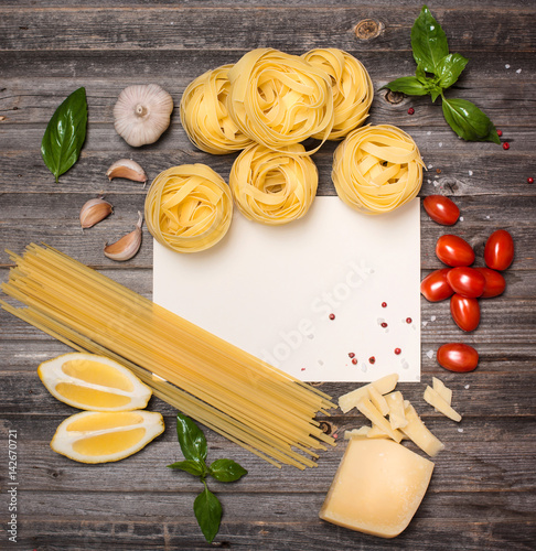 Pasta background with ingredients for cooking around paper, space for text, top view.