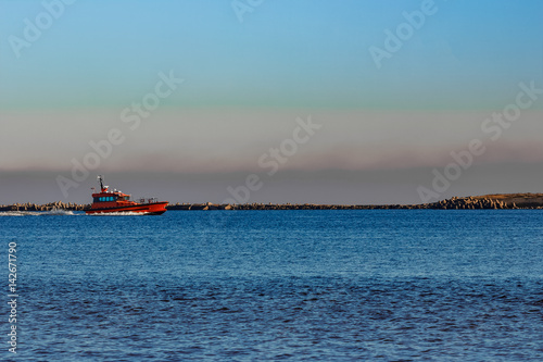 Red pilot ship moving past the breakwater dam in Riga, Europe © InfinitumProdux