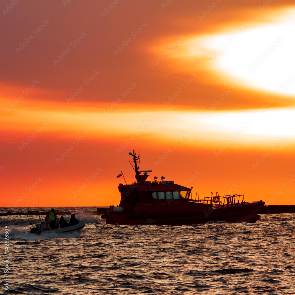 Pilot ship and the dinghy on speed during hot sunset, Latvia Pilot ship and the dinghy on speed during hot sunset, Latvia