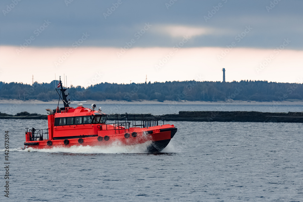 Fototapeta premium Red pilot ship moving at speed to Baltic sea in Riga, Europe