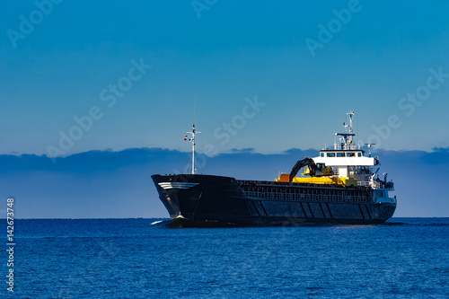 Black cargo ship with long reach excavator moving by baltic sea © InfinitumProdux