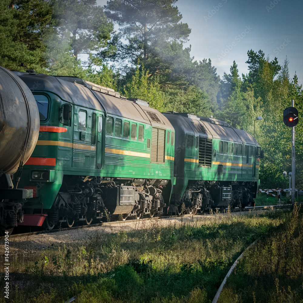 Freight train with tank wagons moving in forest. Green diesel ca Freight train with tank wagons moving in forest. Green diesel ca
