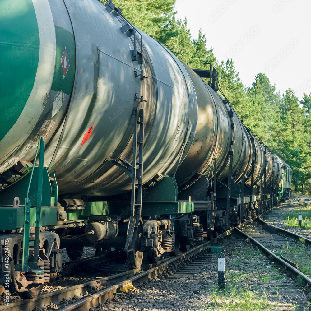 Tank wagons with oil. Freight train in forest Tank wagons with oil. Freight train in forest
