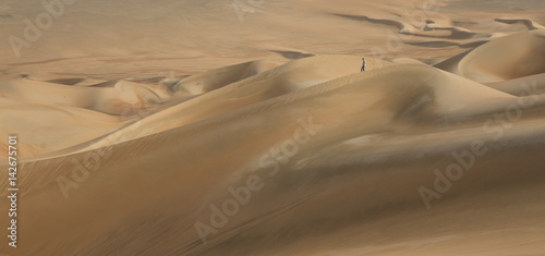 young man walking in the sand dunes of Liwa desert © katiekk2