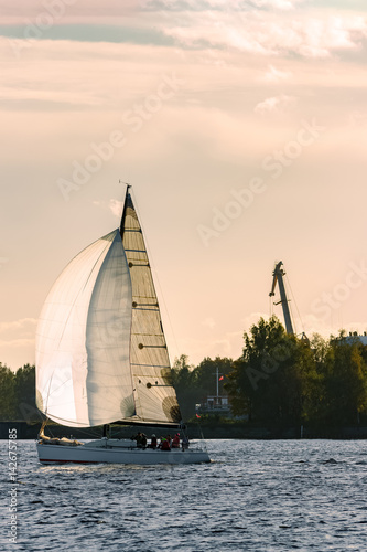 Foto Sailboat moving on Daugava river in evening, Latvia
