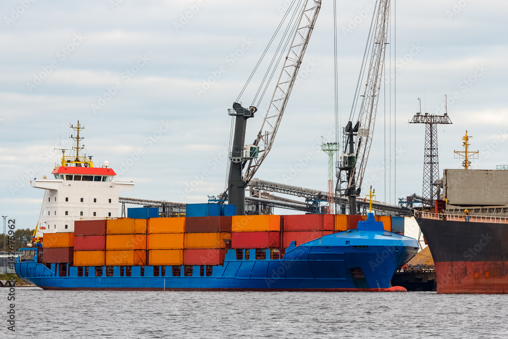 Blue container ship loading in cargo port of Europe Blue container ship loading in cargo port of Europe