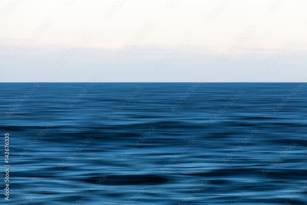 An abstract long exposure pan of the blue ocean and horizon.