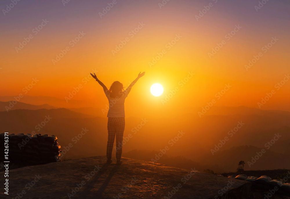          silhoutte young asian women stand raised up arms enjoying to valley view on high cliff  from top of mountain  on sunset 
