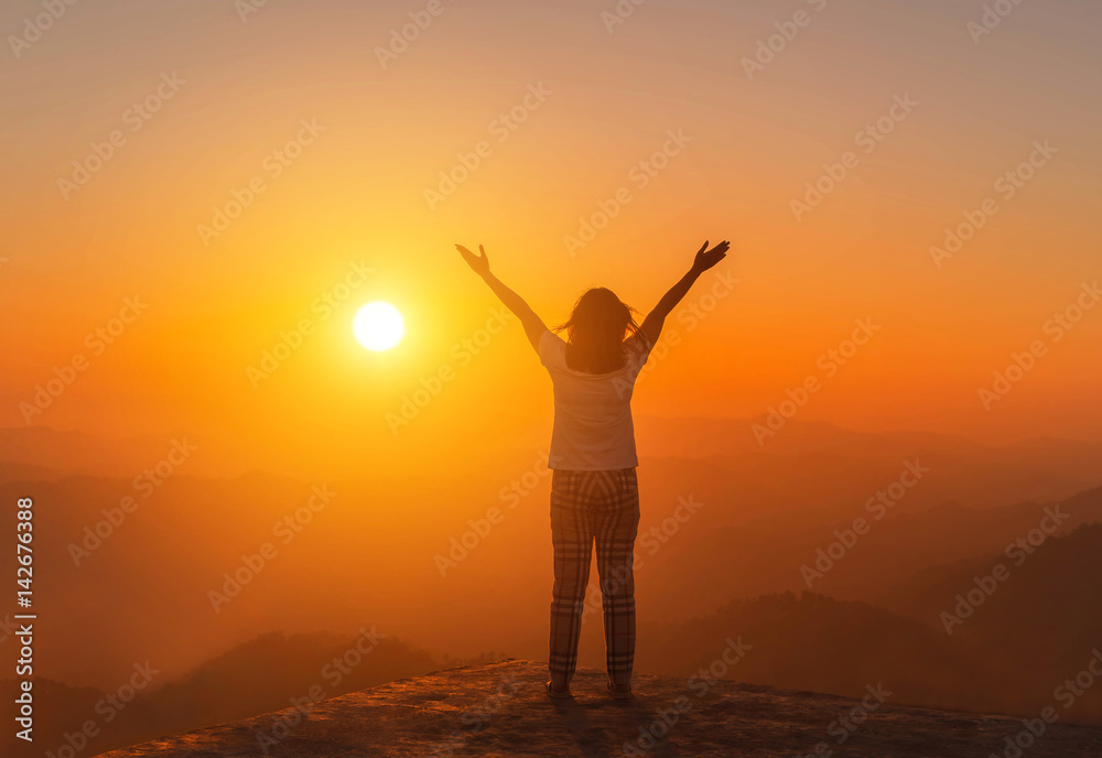          silhoutte young asian women stand raised up arms enjoying to valley view on high   from top of mountain at sunset