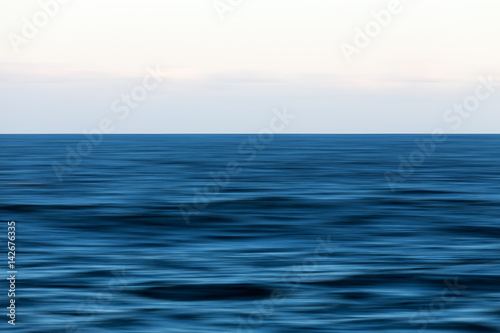 An abstract long exposure pan of the blue ocean and horizon.